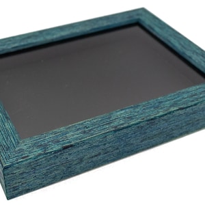 May include: A teal blue shadow box with a black felt interior. The box has a wood grain texture and is perfect for displaying small items.