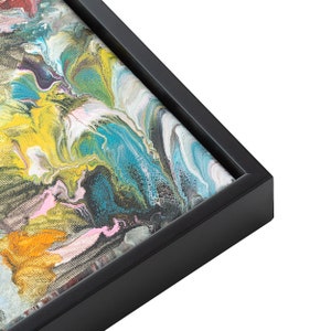 May include: Close-up of a framed abstract painting with swirling colors of yellow, blue, green, pink, and white.