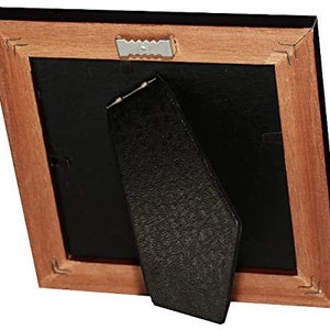 May include: A wooden picture frame with a black mat and a black easel stand. The frame has a dark wood finish and a simple design.