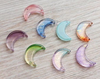 Puede incluir: Surtido de ocho dijes de vidrio en forma de media luna en varios colores, incluyendo rosa, azul, verde, morado y naranja. Los dijes tienen un acabado brillante e iridiscente.