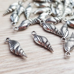 May include: A collection of silver seashell charms featuring intricate details. These charms are ideal for jewellery making or adding a touch of coastal style to crafts.