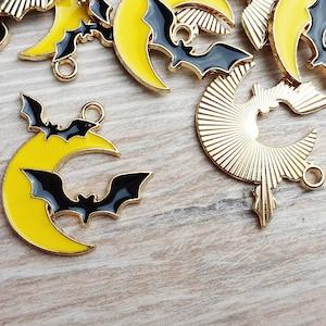 Könnte beinhalten: Eine Sammlung goldfarbener Metall-Anhänger mit einem Halbmond-Design und einer schwarzen Fledermaus. Die Anhänger haben eine glänzende Oberfläche und sind perfekt, um Schmuck oder Bastelarbeiten eine gruselige Note zu verleihen.