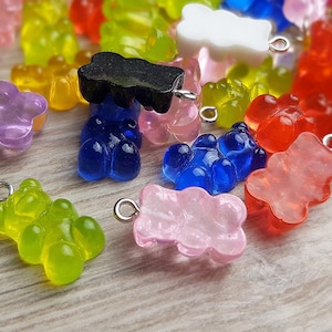 Op de afbeelding: Assortiment van kleurrijke gummy bear bedels met zilveren springringen. De bedels zijn gemaakt van helder plastic en zijn verkrijgbaar in verschillende kleuren, waaronder rood, oranje, geel, groen, blauw, paars, roze en zwart.