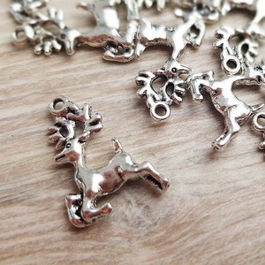 May include: Silver reindeer charms with intricate details. The charms have a loop at the top for attaching to jewelry or other crafts.