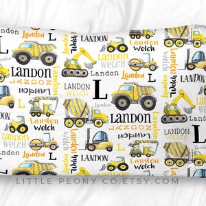 May include: White pillowcase featuring yellow construction vehicles, the name "Landon", and the initial "L". The pillowcase has a repeating pattern of trucks, excavators, and other construction equipment.