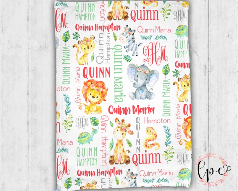 May include: A white baby blanket with a jungle animal theme. The blanket features a repeating pattern of giraffes, zebras, elephants, lions, snakes, and turtles. The blanket is personalized with the name "Quinn" and the initials "HM".