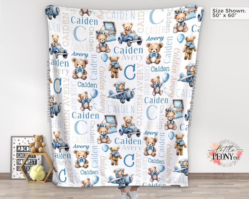 May include: A white baby blanket with a repeating pattern of teddy bears, blue vehicles, and the names "Caiden" and "Avery." The blanket measures 50 inches by 60 inches.