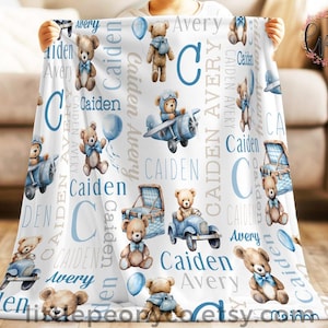 May include: White baby blanket featuring teddy bears, balloons, and the names "Caiden" and "Avery" in blue and gray. The blanket has a repeating pattern of teddy bears in various vehicles and poses.