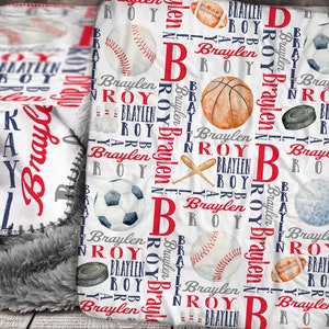 May include: White fleece blanket with a red and blue pattern of sports balls and the name "Braylen" repeated throughout.