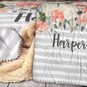 May include: A personalised blanket with the name "Harper" in dark grey lettering. The blanket features a floral design, grey and white stripes, and a plush, tan sherpa backing. The top has a watercolour floral pattern in peach, pink, and white.