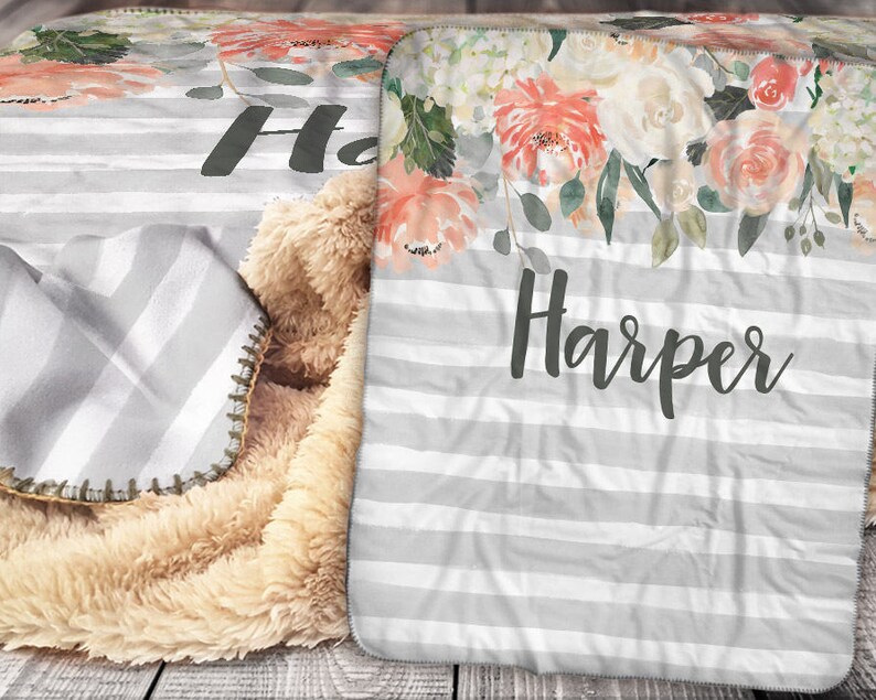 May include: A personalised blanket with the name "Harper" in dark grey lettering. The blanket features a floral design, grey and white stripes, and a plush, tan sherpa backing. The top has a watercolour floral pattern in peach, pink, and white.