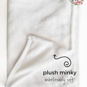 Puede incluir: Una manta de minky blanca, doblada por la mitad, con el texto "plush minky unbelievably soft!" y una peque&ntilde;a flecha que apunta al tejido.