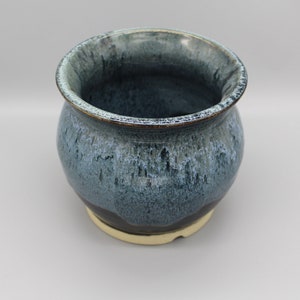 May include: A blue and black ceramic planter with a gold rim. The planter has a speckled glaze and a rounded shape.