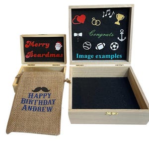 May include: Two light-colored wooden boxes with hinged lids and black interior linings. The smaller box lid interior reads Merry Beardmas with a Santa icon. A burlap drawstring bag reads HAPPY BIRTHDAY ANDREW. The larger box lid shows various icons.