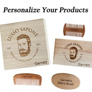 May include: A set of personalized wooden beard care products with the name "Garrett" engraved on each item. The set includes a wooden box, a comb, a brush, and a smaller wooden box. The boxes feature a logo with a man's face and the text "Lusso Sapone Est 2017 Beard Oil Beard Balm And Soaps".