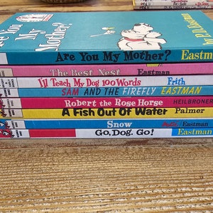 May include: A stack of ten colorful children's books with various titles, including "Are You My Mother?" by P.D. Eastman, "The Best Nest" by P.D. Eastman, "I'll Teach My Dog 100 Words" by Frith, "Sam and the Firefly" by Eastman, "Robert the Rose Horse" by Heilbroner, "A Fish Out of Water" by Palmer, "Snow" by P.D. Eastman, and "Go, Dog, Go!" by P.D. Eastman.