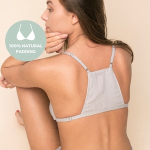 Könnte beinhalten: Ein graues Leinen-Bralette mit verstellbaren Trägern. Das Bralette hat einen V-förmigen Rücken und ist mit 100% natürlicher Polsterung ausgestattet.