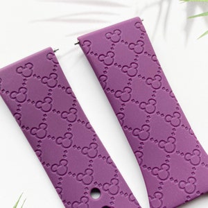 May include: Two purple silicone watch straps with a Mickey Mouse pattern. The straps have a repeating pattern of Mickey Mouse heads and a checkered design.