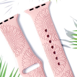 May include: A pair of pink silicone Apple Watch bands with a sunflower design. The bands are made of soft, comfortable silicone and are compatible with most Apple Watch models.