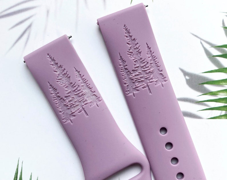 May include: Two purple silicone watch bands with a raised design of three pine trees.