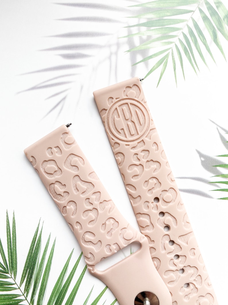 May include: Two pink silicone watch bands with a leopard print design. One band has a monogrammed circle with the initials "CBO" in the center.