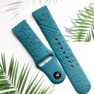 K&ouml;nnte beinhalten: Zwei tealblaue Silikon-Armb&auml;nder mit gepr&auml;gten Star Wars-Charakteren und dem Text "Star Wars".