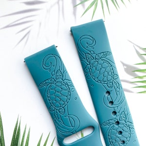 May include: Two teal blue silicone watch bands with a sea turtle design. The bands have a raised design of a sea turtle swimming in the ocean.