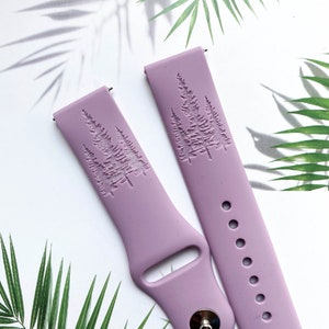 May include: Two lavender silicone watch bands with a raised design of three pine trees. The bands have a silver metal buckle and a row of holes for adjusting the fit.