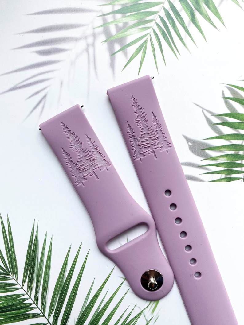 May include: Two lavender silicone watch bands with a raised design of three pine trees. The bands have a silver metal buckle and a row of holes for adjusting the fit.