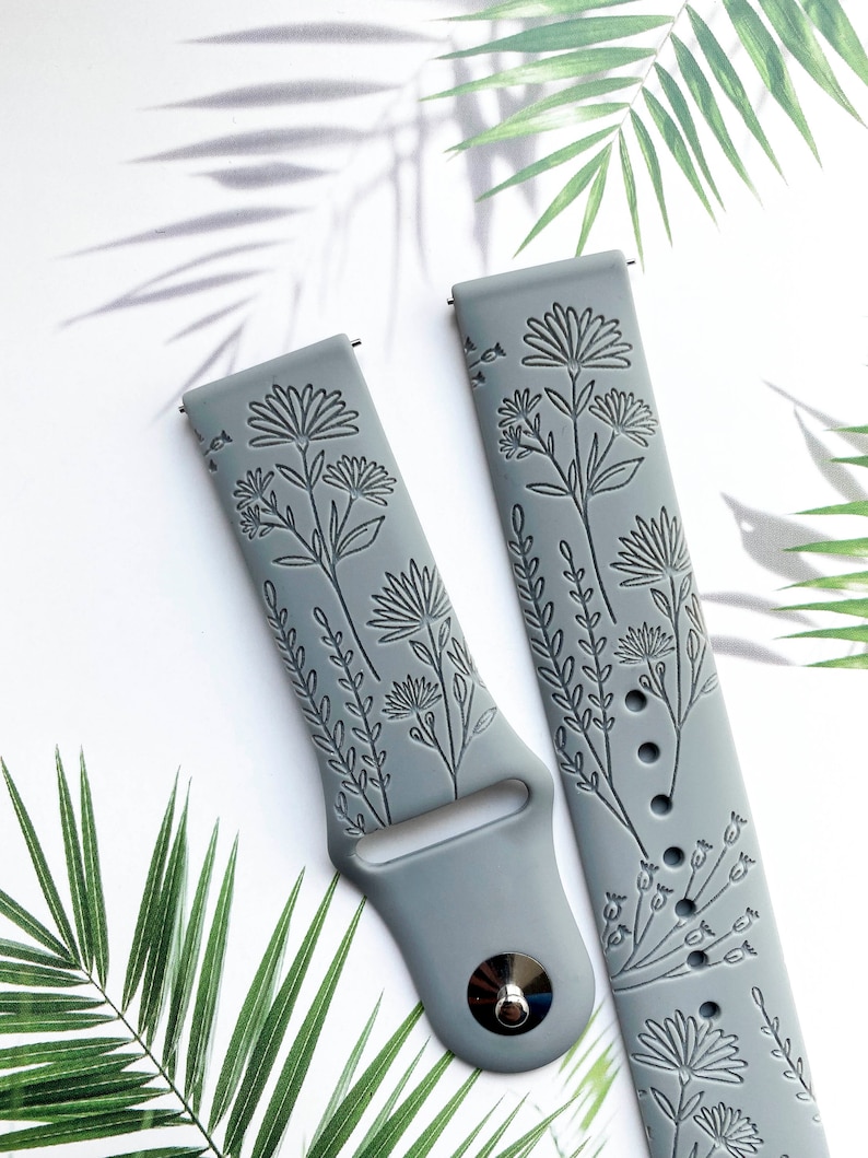 May include: Two gray silicone watch bands with an embossed floral design. The bands are made of a soft, flexible material and are compatible with most smartwatches.