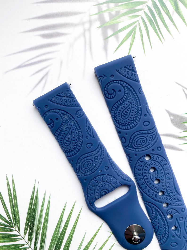 May include: A pair of blue silicone watch bands with a paisley pattern. The bands are designed for smartwatches.