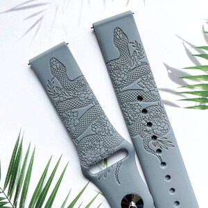 May include: Two gray silicone watch bands with a snake and floral design. The bands are embossed with a detailed snake and floral pattern.