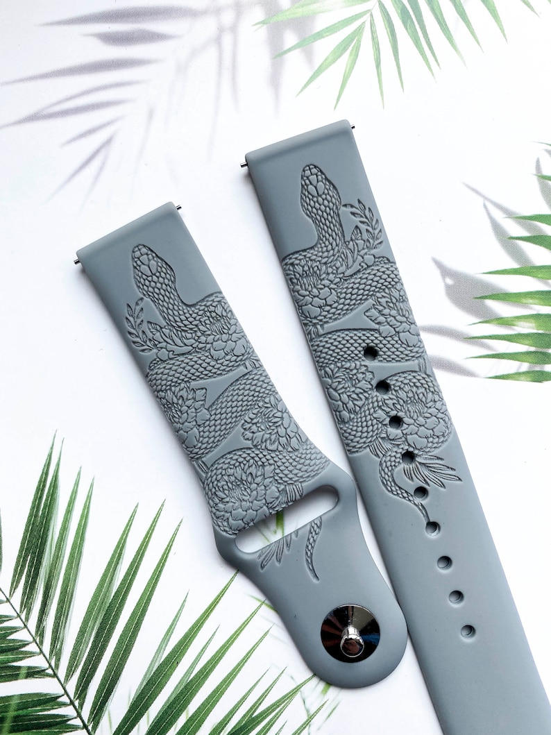 May include: Two gray silicone watch bands with a snake and floral design. The bands are embossed with a detailed snake and floral pattern.