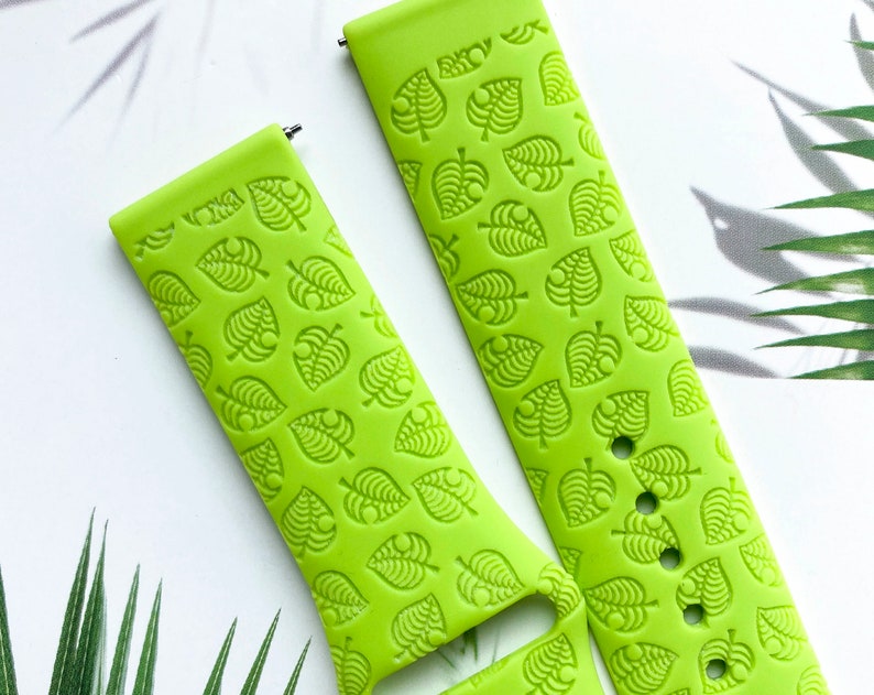 May include: A bright green silicone watch band with a repeating pattern of green leaves. The band is designed for a smartwatch.