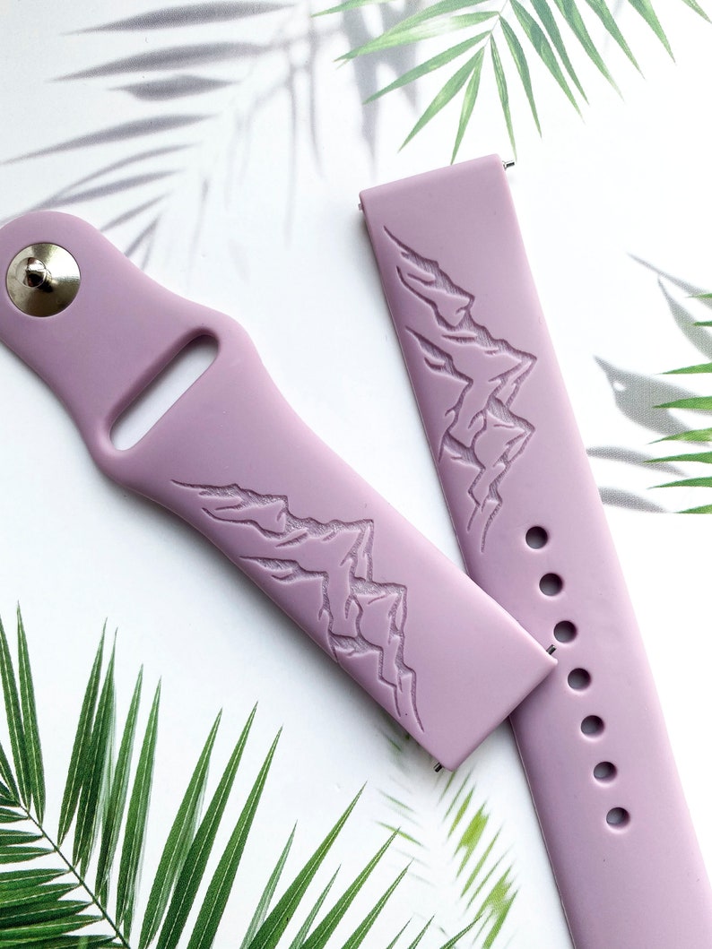 K&ouml;nnte beinhalten: Zwei lavendelfarbene Silikon-Armb&auml;nder mit einem gepr&auml;gten Bergketten-Design auf der Vorderseite. Die Armb&auml;nder sind f&uuml;r Smartwatches konzipiert.