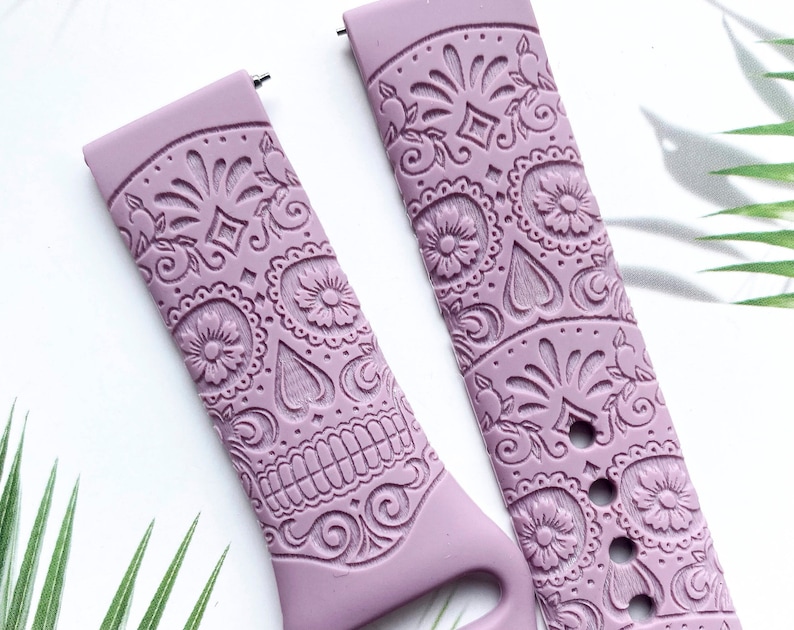 Pu&ograve; includere: Due cinturini per orologio in silicone color lilla con un design a teschio di zucchero. I cinturini hanno un motivo in rilievo e sono progettati per uno smartwatch.