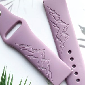 May include: A lilac silicone watch band with a mountain range design embossed on the strap.