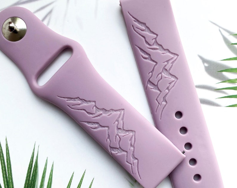 K&ouml;nnte beinhalten: Ein lilafarbenes Silikon-Armband mit einem gepr&auml;gten Bergketten-Design auf dem Band.
