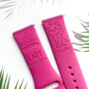 Op de afbeelding: Twee roze siliconen horlogebandjes met gegraveerde ontwerpen. E&eacute;n bandje heeft een cartoonkat met de tekst "I'm a lady". Het andere bandje heeft een strik en de tekst "Because I'm a lady that's why!"