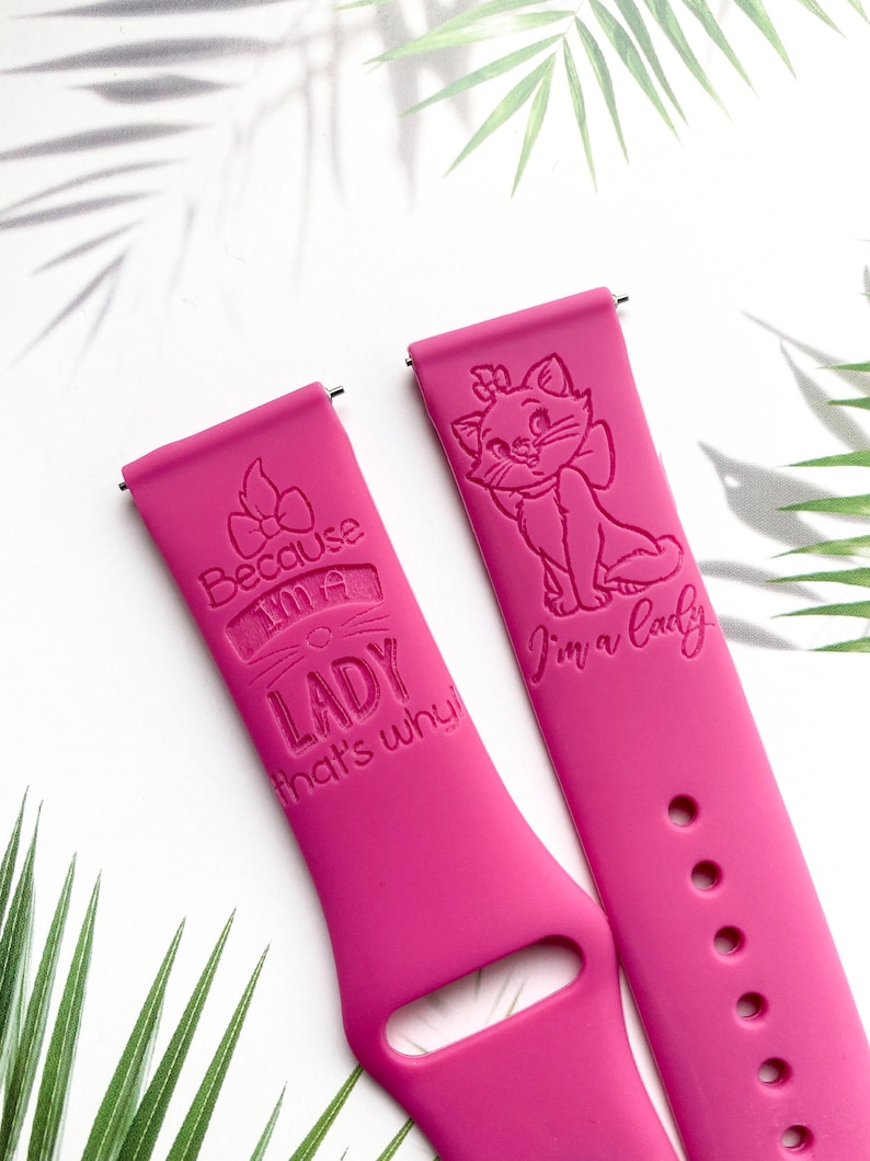 Op de afbeelding: Twee roze siliconen horlogebandjes met gegraveerde ontwerpen. E&eacute;n bandje heeft een cartoonkat met de tekst "I'm a lady". Het andere bandje heeft een strik en de tekst "Because I'm a lady that's why!"