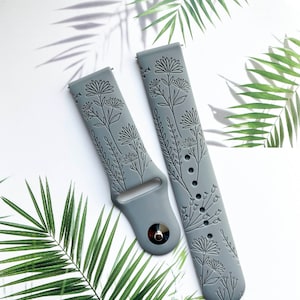 May include: Two gray silicone watch bands with a floral design. The bands are embossed with a delicate floral pattern.