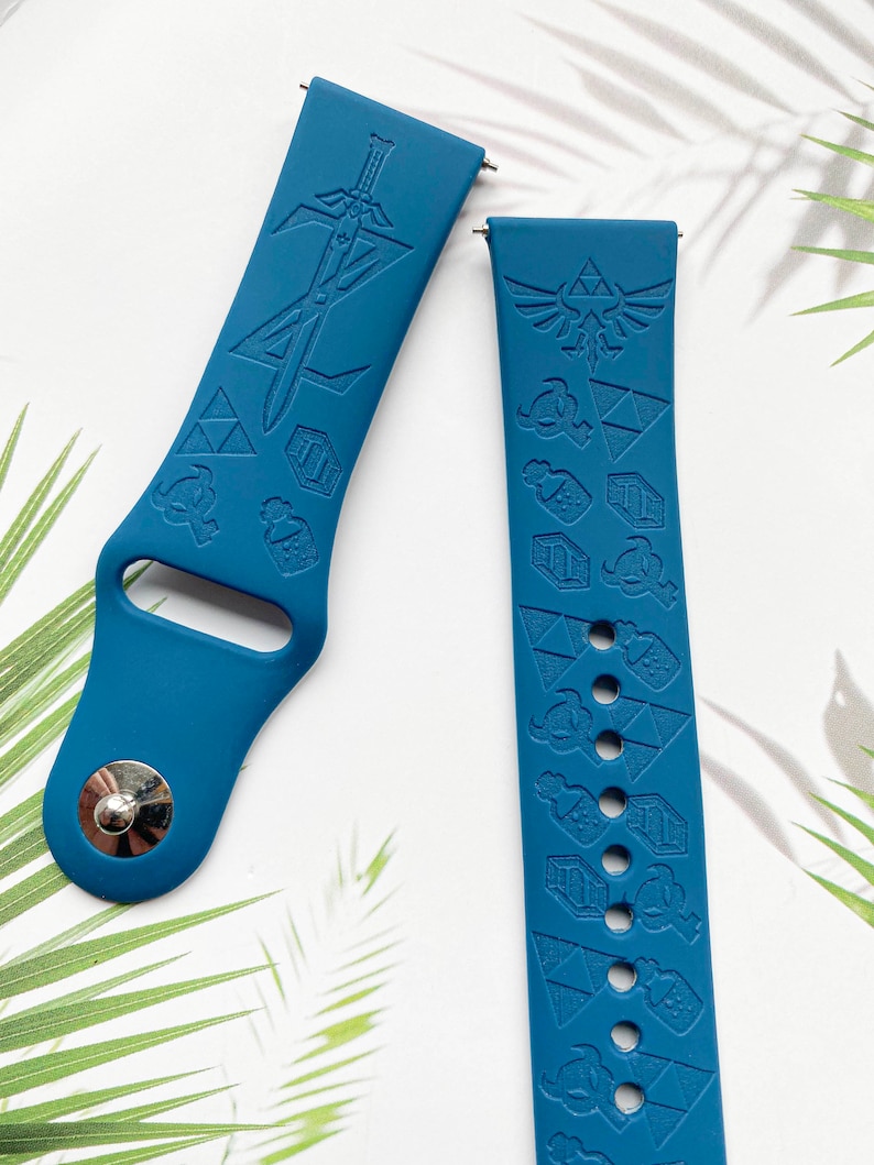 Op de afbeelding: Twee blauwe siliconen horlogebandjes met een Zelda-thema. E&eacute;n bandje heeft een zwaard en het andere heeft een Triforce en andere Zelda-symbolen.