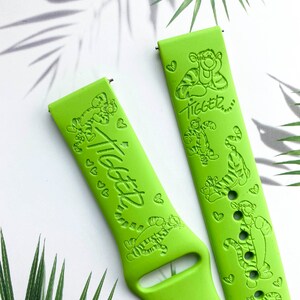 May include: Two green silicone watch bands with a Tigger design. The bands feature a repeating pattern of Tigger and hearts. The text "Tigger" is embossed on the bands.