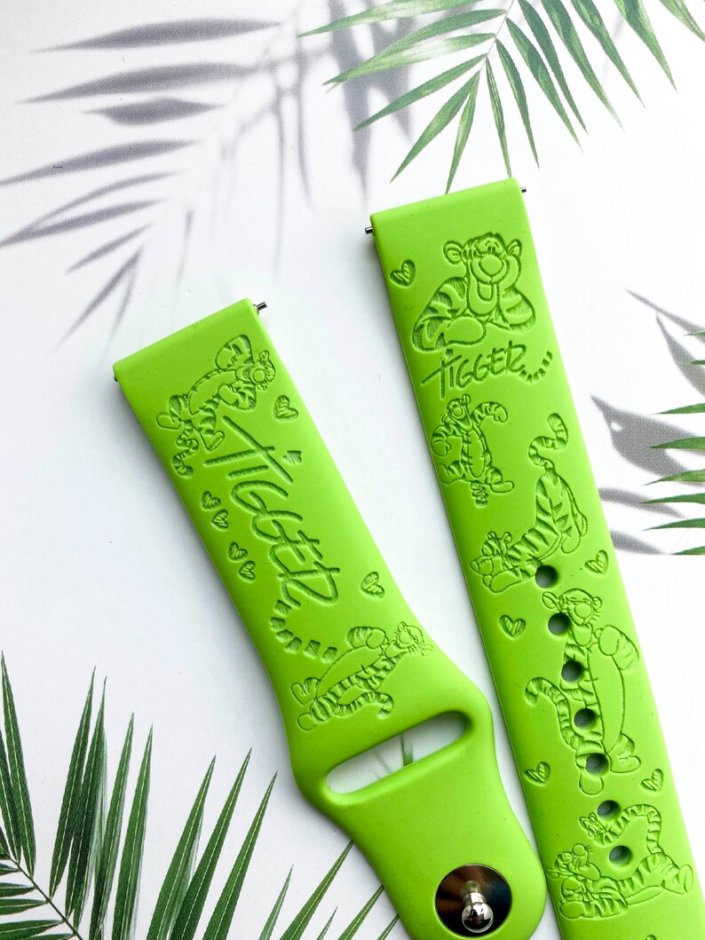May include: Two green silicone watch bands with a Tigger design. The bands feature a repeating pattern of Tigger and hearts. The text "Tigger" is embossed on the bands.