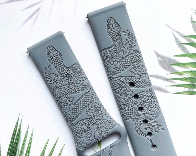 May include: Two gray silicone watch bands with a snake and floral design. The bands are embossed with a detailed snake design and floral accents.