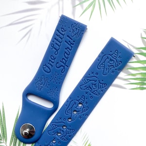 May include: A blue silicone watch band with a white print that says "One Little Spark!" and a unicorn design.
