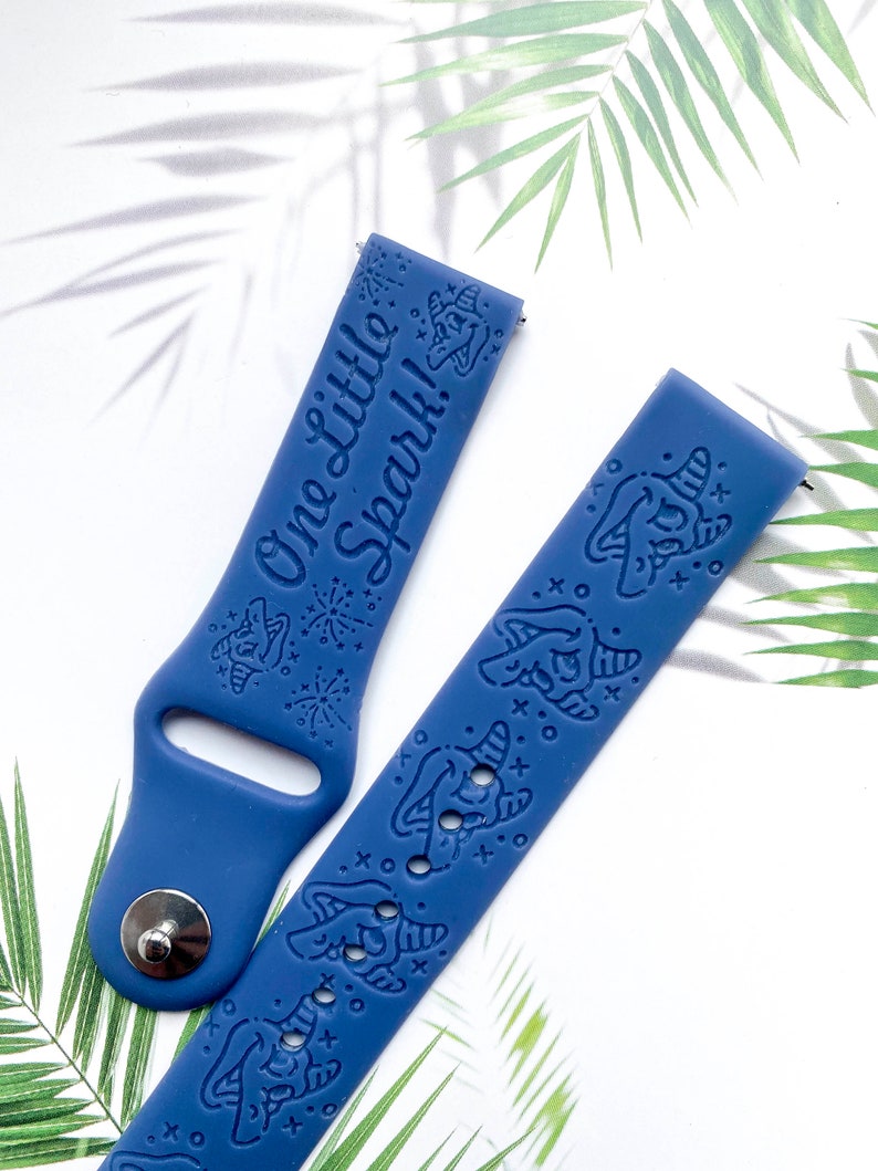 May include: A blue silicone watch band with a white print that says "One Little Spark!" and a unicorn design.