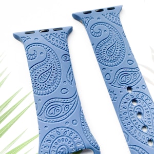 May include: Two blue silicone watch straps with a paisley pattern. The straps are designed for Apple Watches.