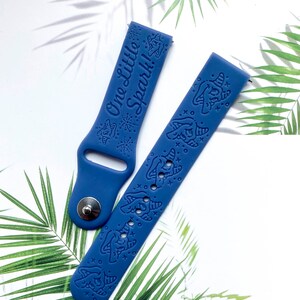 May include: Two blue silicone watch bands with a unicorn design and the text "One Little Spark!" on one band.
