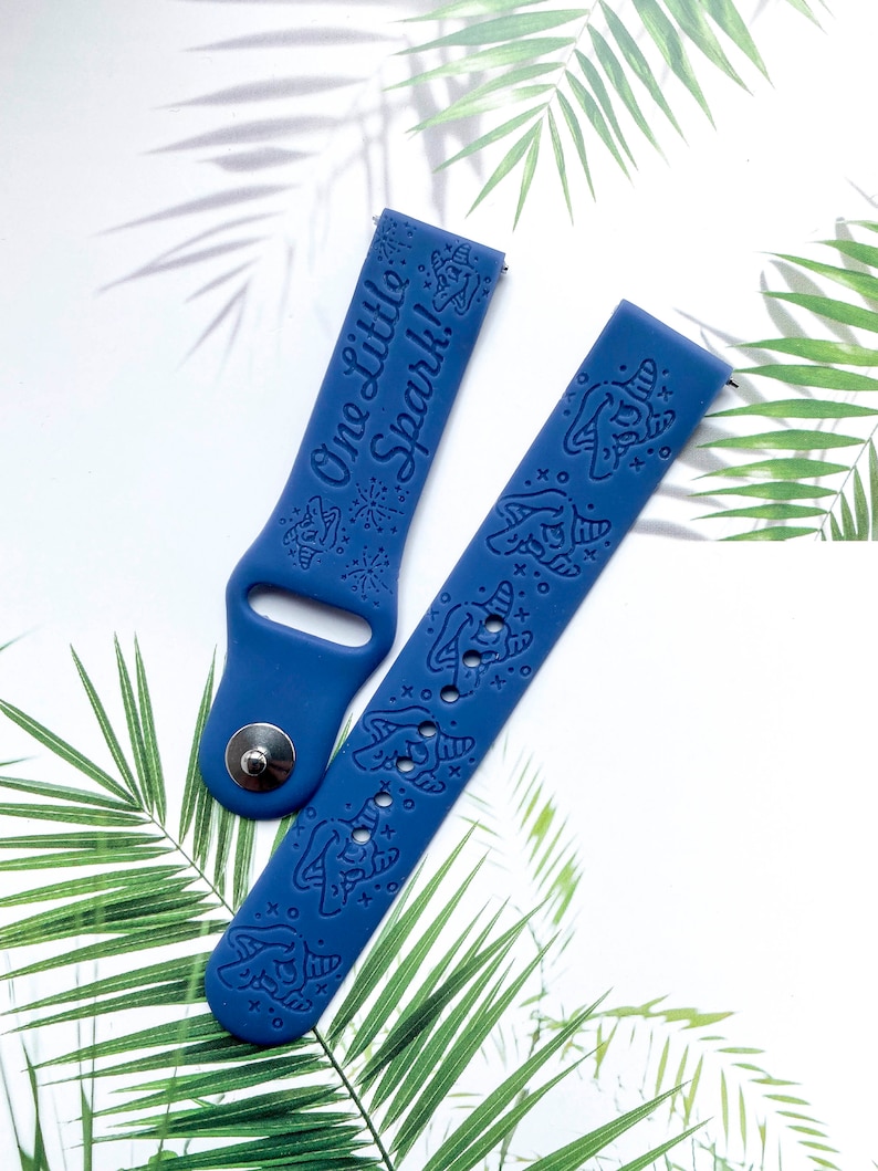 May include: Two blue silicone watch bands with a unicorn design and the text "One Little Spark!" on one band.